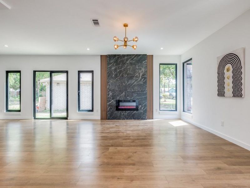 Unfurnished living room featuring light hardwood / wood-style floors, a fireplace, and a notable chandelier