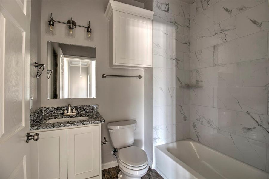 Full bathroom featuring tiled shower / bath, vanity, toilet, and hardwood / wood-style floors