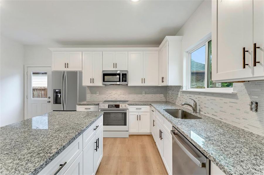 Ample Counter and Storage Space - The kitchen features a sizable island, ample countertops, and stainless steel appliances.