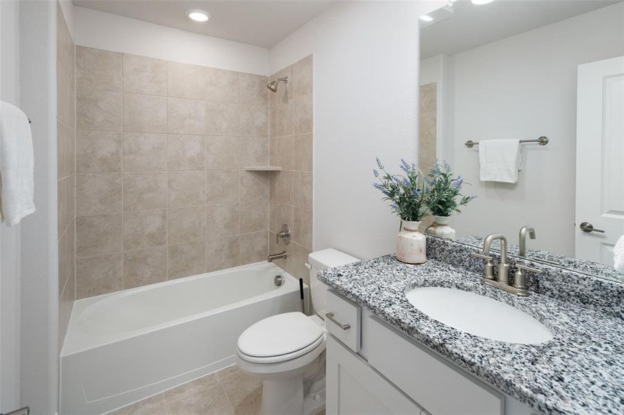 Full bathroom with tile patterned flooring, vanity, toilet, and tiled shower / bath combo