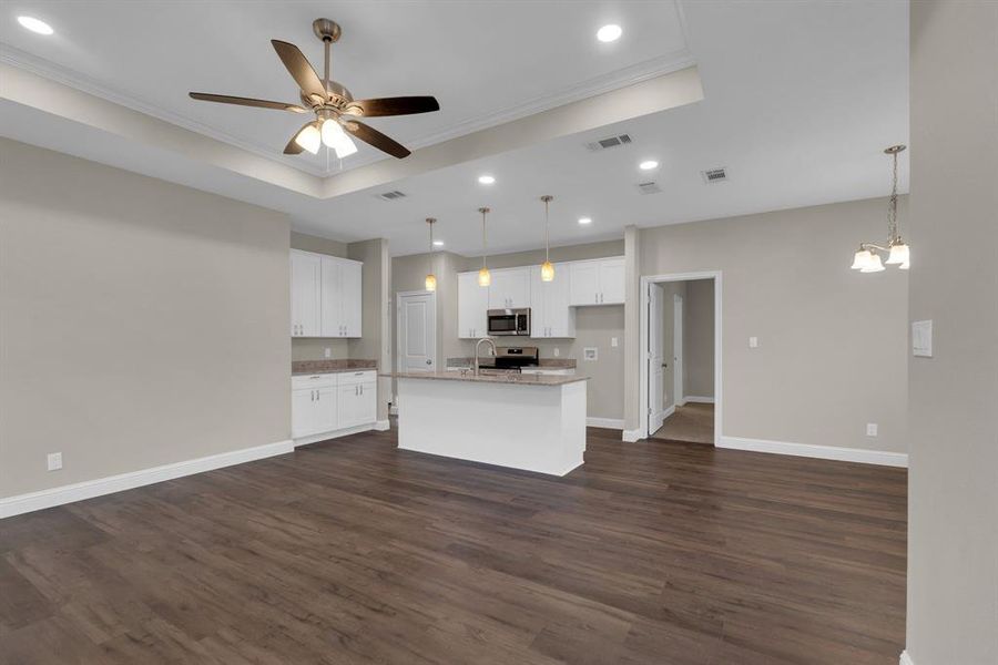 Kitchen featuring dark hardwood / wood-style flooring, a kitchen island with sink, stainless steel appliances, and white cabinets