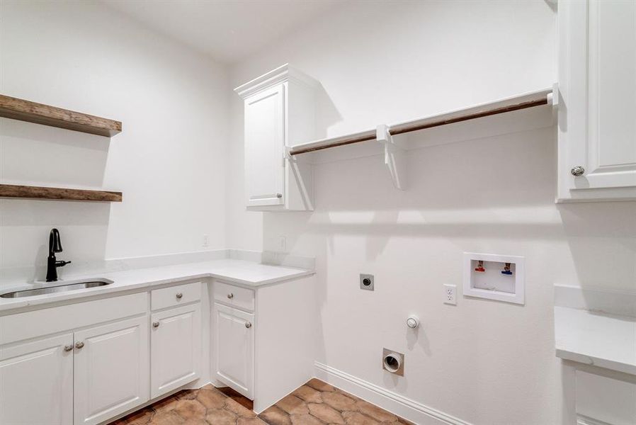 Clothes washing area with hookup for a gas dryer, hookup for a washing machine, sink, electric dryer hookup, and cabinets