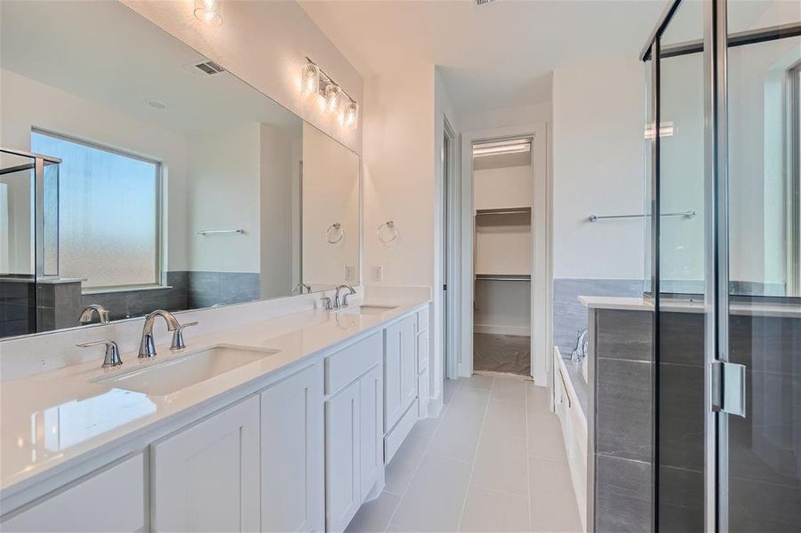 Primary en suite bathroom featuring walk in shower, vanity, and tile patterned floors