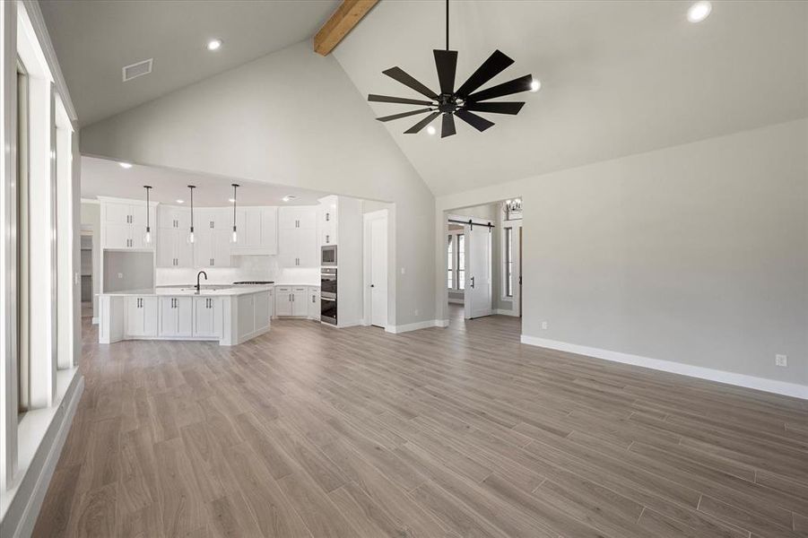 Living room featuring a vaulted ceiling with a beam, big windows letting in natural light, vaulted ceiling with beam, ceiling fan, and open floorplan