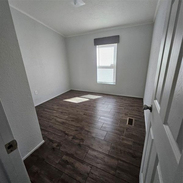 Unfurnished room with crown molding, a textured ceiling, and dark hardwood / wood-style floors