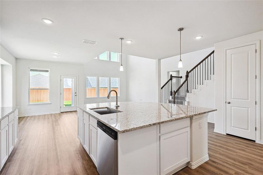 Kitchen with stainless steel dishwasher, white cabinetry, sink, and a wealth of natural light