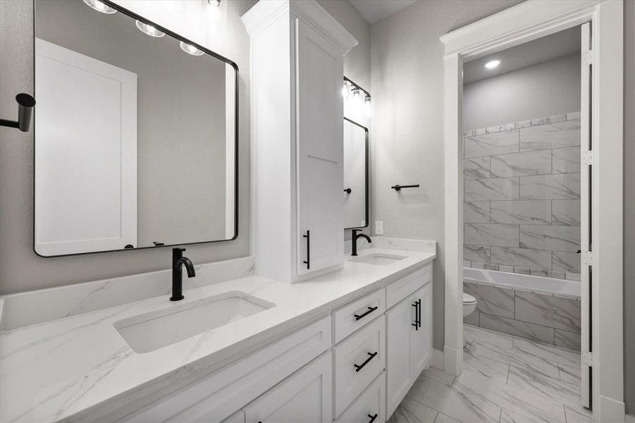 Full bathroom featuring storage, tiled shower / bath combo, and double vanity