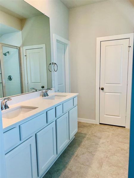 Master bath with quartz countertops, double sinks, tile floors, walk in closet.