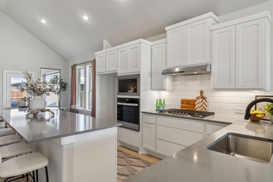 Kitchen featuring stainless steel appliances, light hardwood / wood-style floors, sink, a kitchen breakfast bar, and white cabinets