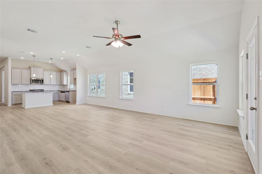 Unfurnished living room with vaulted ceiling, light hardwood / wood-style flooring, and ceiling fan