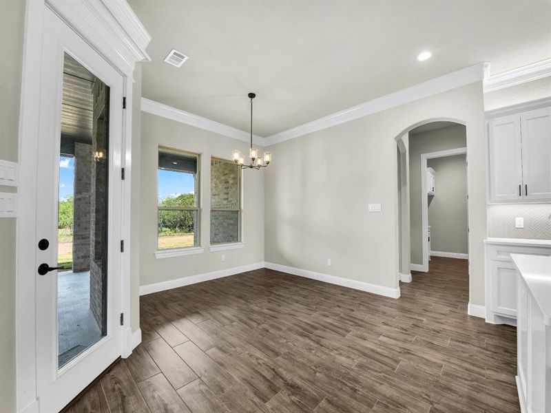 Unfurnished dining area featuring crown molding, an inviting chandelier, and dark hardwood / wood-style floors