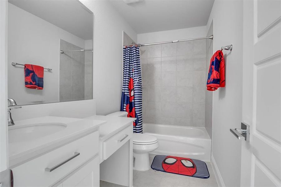 Full bathroom with tile flooring, shower / bath combination with curtain, toilet, and large vanity