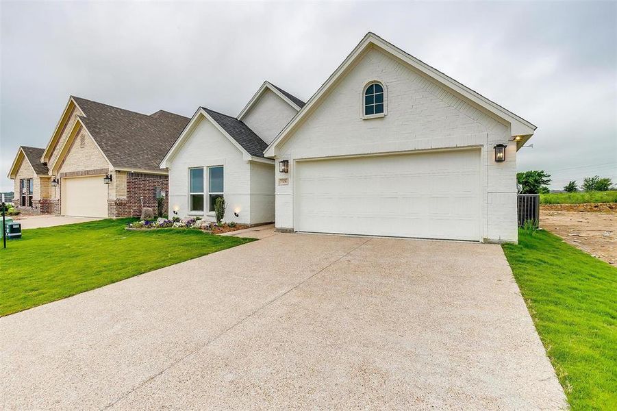 View of front of house featuring a front lawn, central air condition unit, and a garage