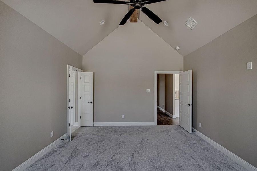 Unfurnished bedroom featuring carpet flooring, high vaulted ceiling, and ceiling fan