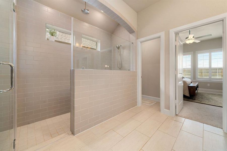 Experience luxurious bathing experiences in the showcased custom walk-in shower with tile surround, and double shower heads.