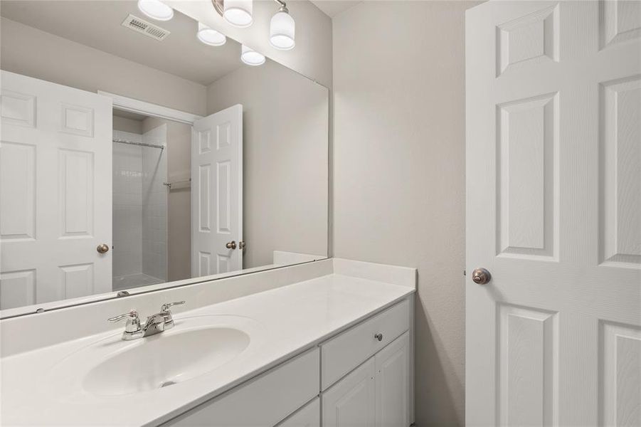 The secondary bath features tile flooring, white cabinetry and light countertops and a shower/tub combo. Perfect for accommodating any visiting family and friends.