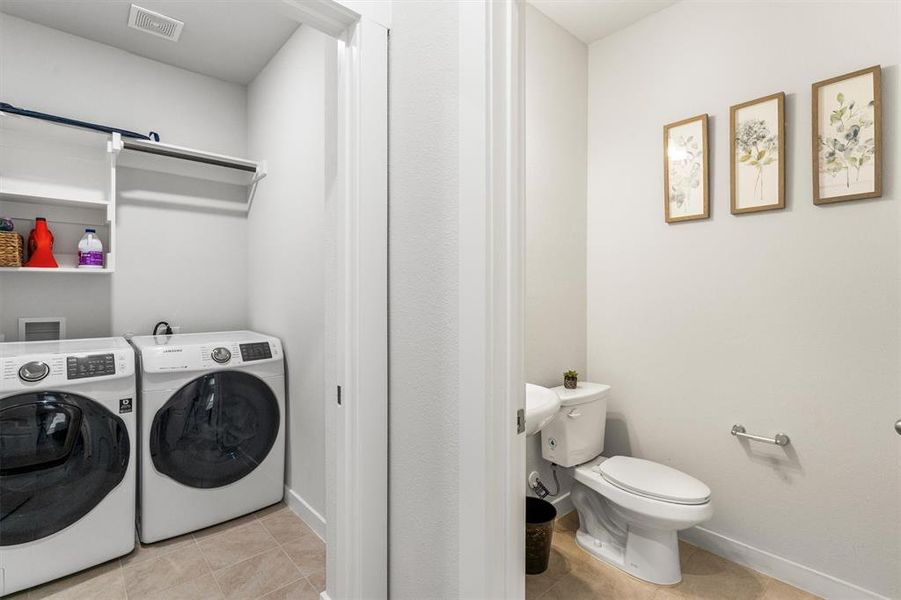 Laundry area featuring light tile patterned flooring and washing machine and clothes dryer