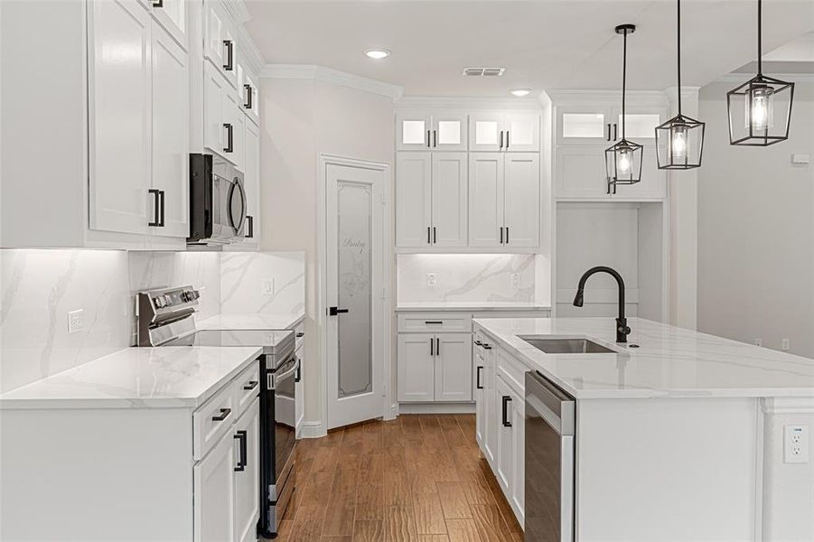 Kitchen featuring light hardwood / wood-style flooring, stainless steel appliances, sink, decorative backsplash, and ornamental molding