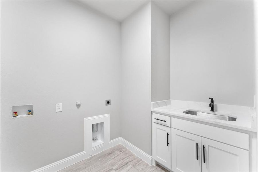 Laundry area featuring washer hookup, hookup for an electric dryer, light wood-type flooring, cabinets, and sink