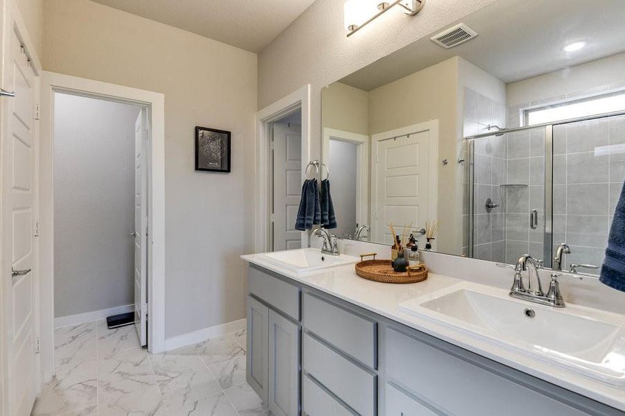 Primary en-suite includes tile flooring, oversized vanity with double sinks, and a spacious walk-in shower.