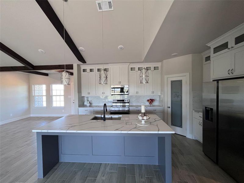 Kitchen featuring appliances with stainless steel finishes, sink, and white cabinetry