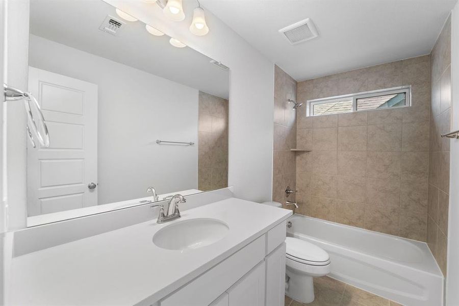 Full bathroom with tiled shower / bath, oversized vanity, toilet, and tile floors