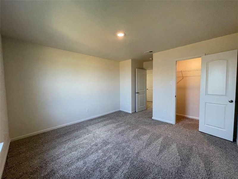 Unfurnished bedroom with a spacious closet, a closet, and dark colored carpet