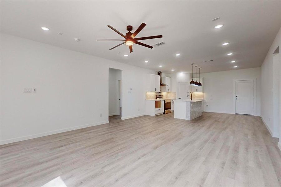 Unfurnished living room featuring sink, ceiling fan, and light hardwood / wood-style floors