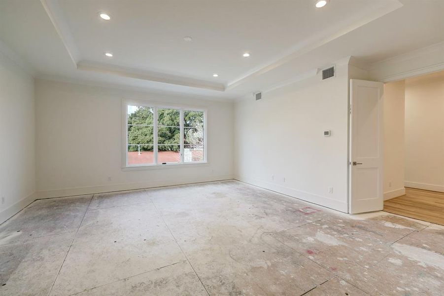 Alternate view of the primary suite from the bathroom shows how light and bright the room is with all the natural light that flows in. We love the crown molding in this room and the double doors leading to this suite!