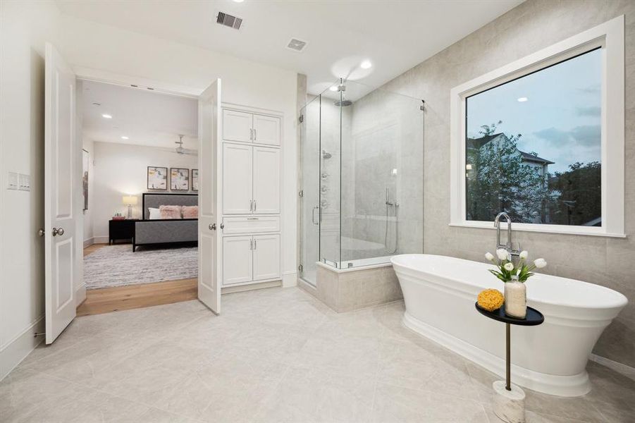 Soaking Tub with Floor Mounted Tub Filler, 12 x 24 Silver Matt Tile (from Emser Tile) Surround on the Wall. Large Walk-In Shower with Frameless Shower Door, Rain Shower Head, Wall Mounted Shower Head and a Hand Held Shower Head. The Shower is surrounded with 12 x 24 Silver Matte Tile (from Emser Tile) to match the adjacent wall. There is also a large built-in linen storage closet.