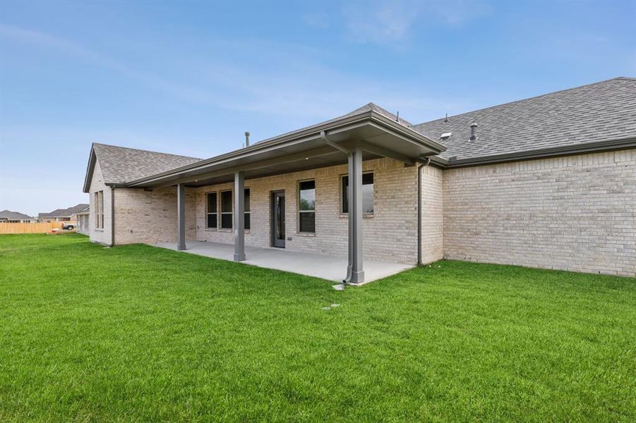 Rear view of house with a lawn and a patio