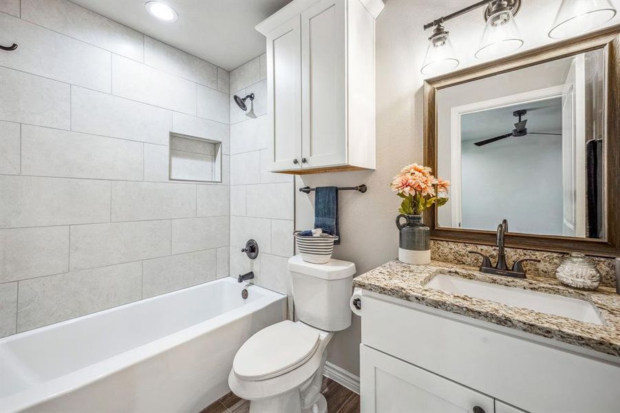 Full bathroom featuring tiled shower / bath, vanity, toilet, and hardwood / wood-style flooring