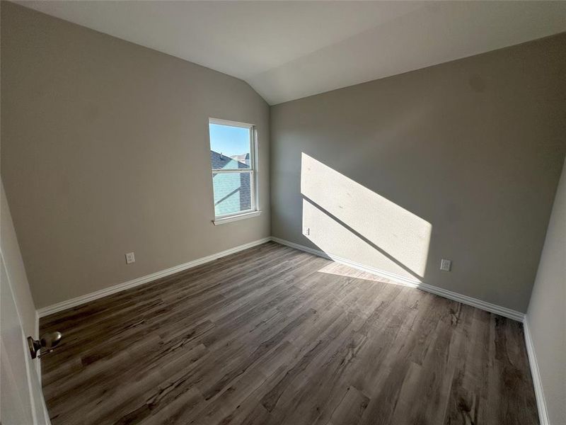 Empty room featuring lofted ceiling and hardwood / wood-style floors