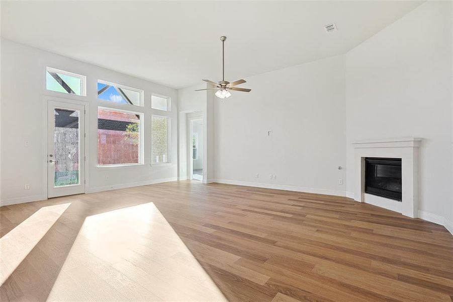 Unfurnished living room featuring light wood-type flooring, ceiling fan, and plenty of natural light