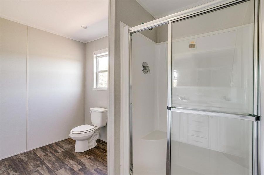 Bathroom with a shower with shower door, toilet, and hardwood / wood-style floors