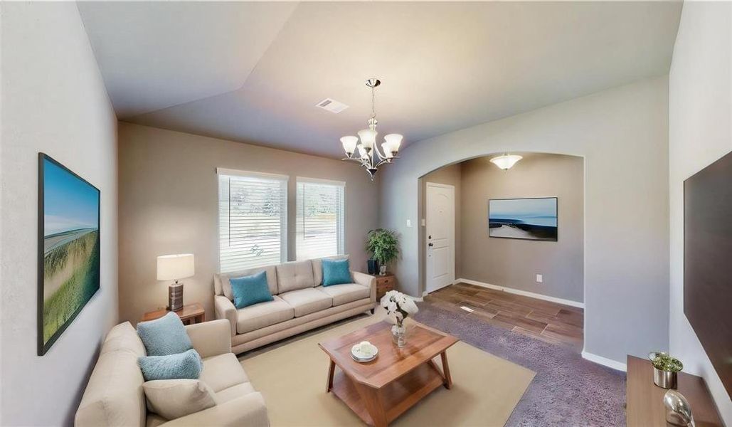 This inviting front entry area sets the tone for the rest of the home, showcasing a welcoming chandelier and large windows that flood the space with natural light. The neutral wall colors and plush carpeting create a warm and cozy atmosphere, making guests feel at home the moment they step inside. This is a picture of an Elise Floor Plan with another Saratoga Homes.