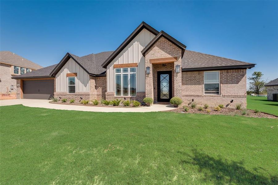 View of front of property featuring a front lawn and a garage