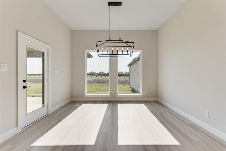 Unfurnished dining area featuring light hardwood / wood-style floors and a notable chandelier