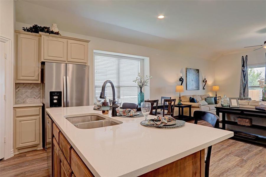 Kitchen with sink, a center island with sink, light wood-type flooring, and stainless steel fridge with ice dispenser