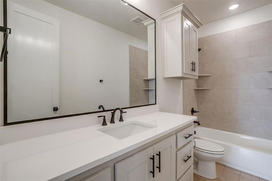 Full bathroom featuring vanity, tile patterned floors, tiled shower / bath, and toilet