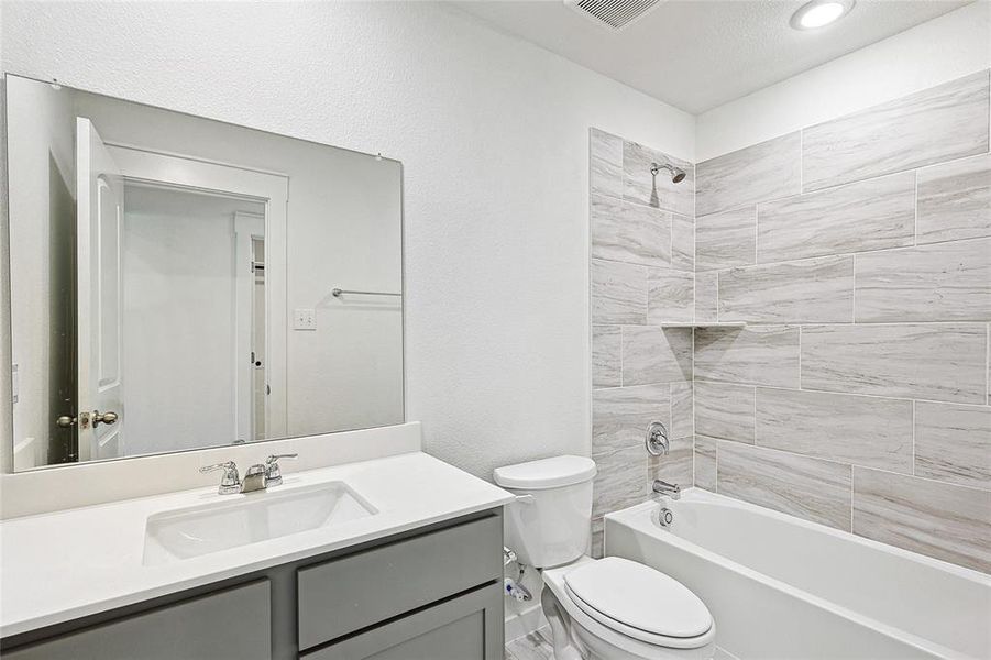 Full bathroom featuring tiled shower / bath, toilet, a textured ceiling, and vanity