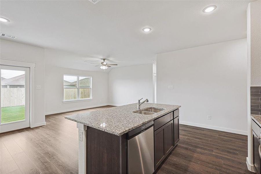 Kitchen with a kitchen island with sink, dark wood-type flooring, sink, stainless steel dishwasher, and ceiling fan