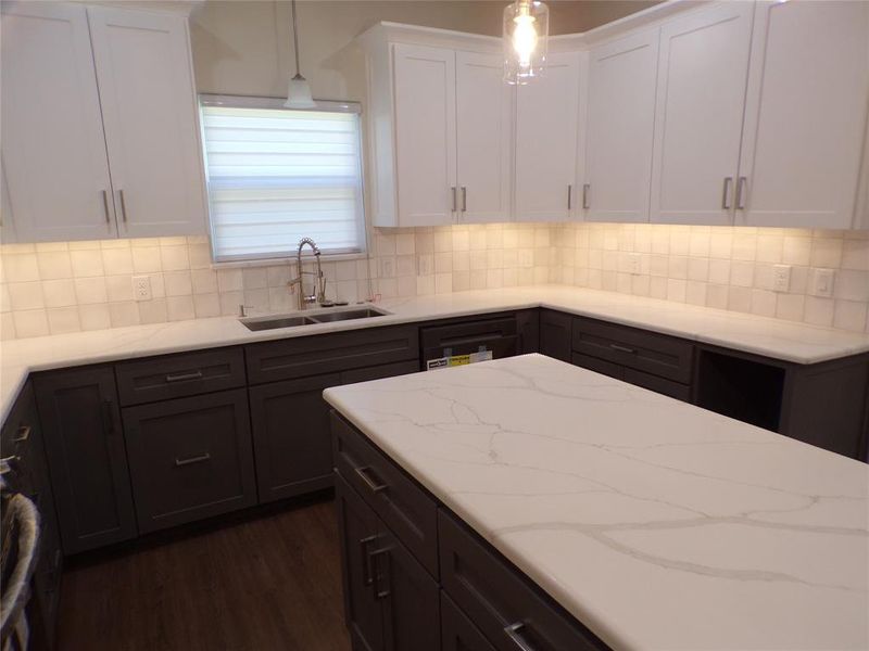 Kitchen with white cabinetry, dark hardwood / wood-style flooring, pendant lighting, sink, and backsplash