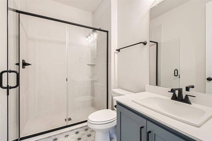 Bathroom featuring vanity, a shower with shower door, and toilet