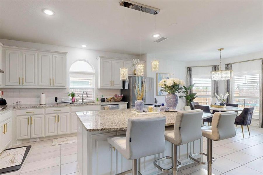 Kitchen featuring light stone countertops, decorative light fixtures, a kitchen island, and white cabinets