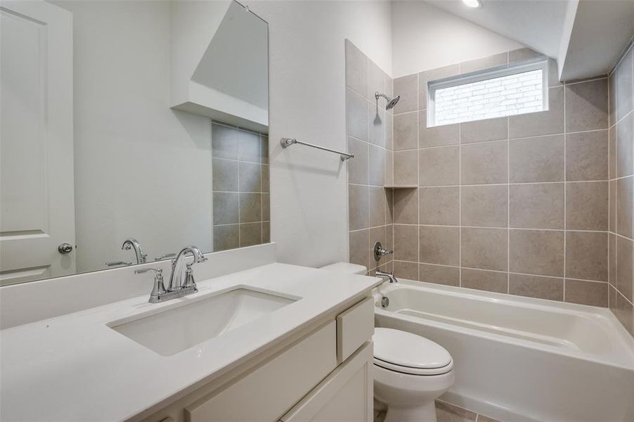 Full bathroom featuring vanity, tiled shower / bath combo, and toilet