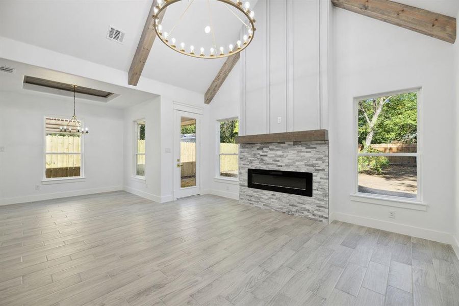 Unfurnished living room featuring light hardwood / wood-style floors, a healthy amount of sunlight, and beam ceiling