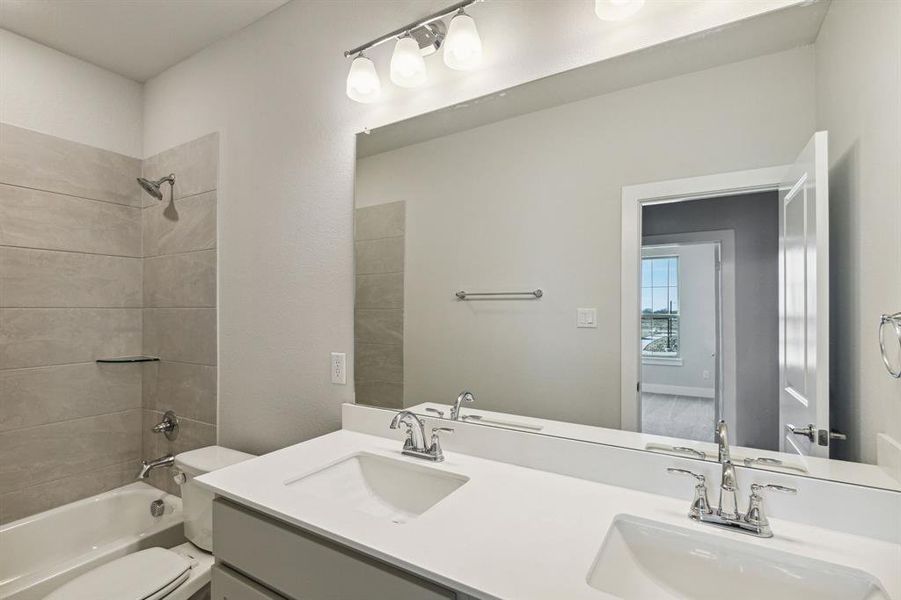 Full bathroom featuring vanity, tiled shower / bath, and toilet