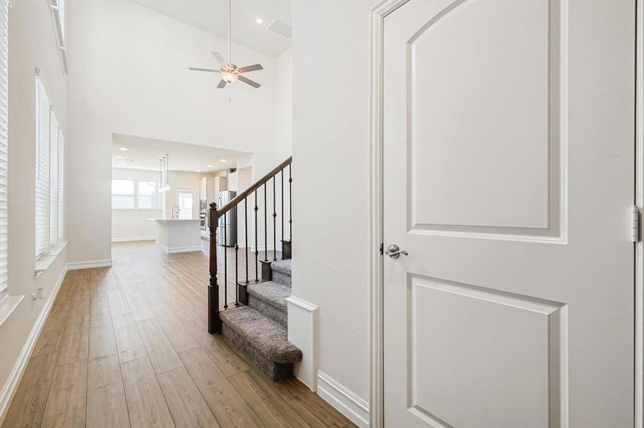 Entryway with ceiling fan, light wood-type flooring, and high vaulted ceiling