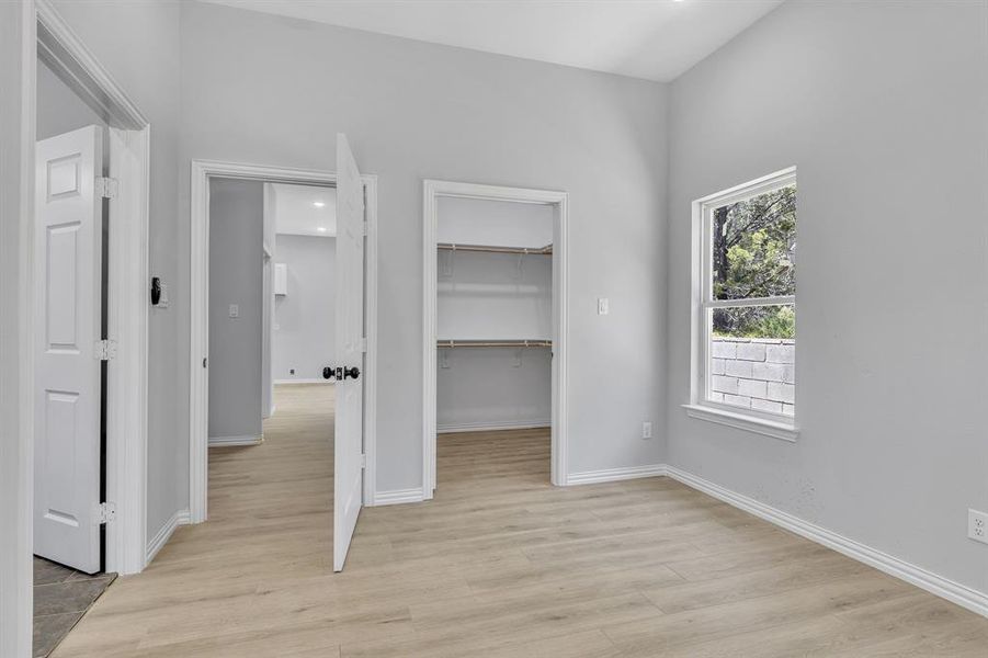Unfurnished bedroom with a closet, light hardwood / wood-style flooring, and a spacious closet